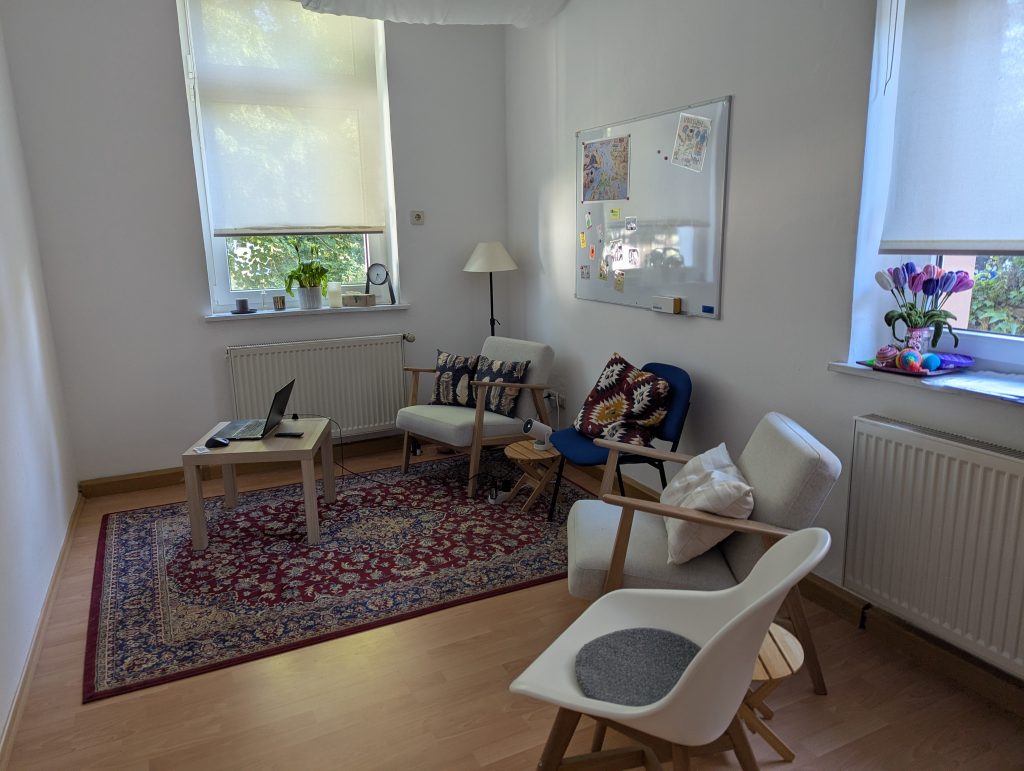 Kleiner Praxisraum mit Stühlen, Tisch und Whiteboard, vorbereitet für eine Fortbildung im Verstehensraum Erlangen